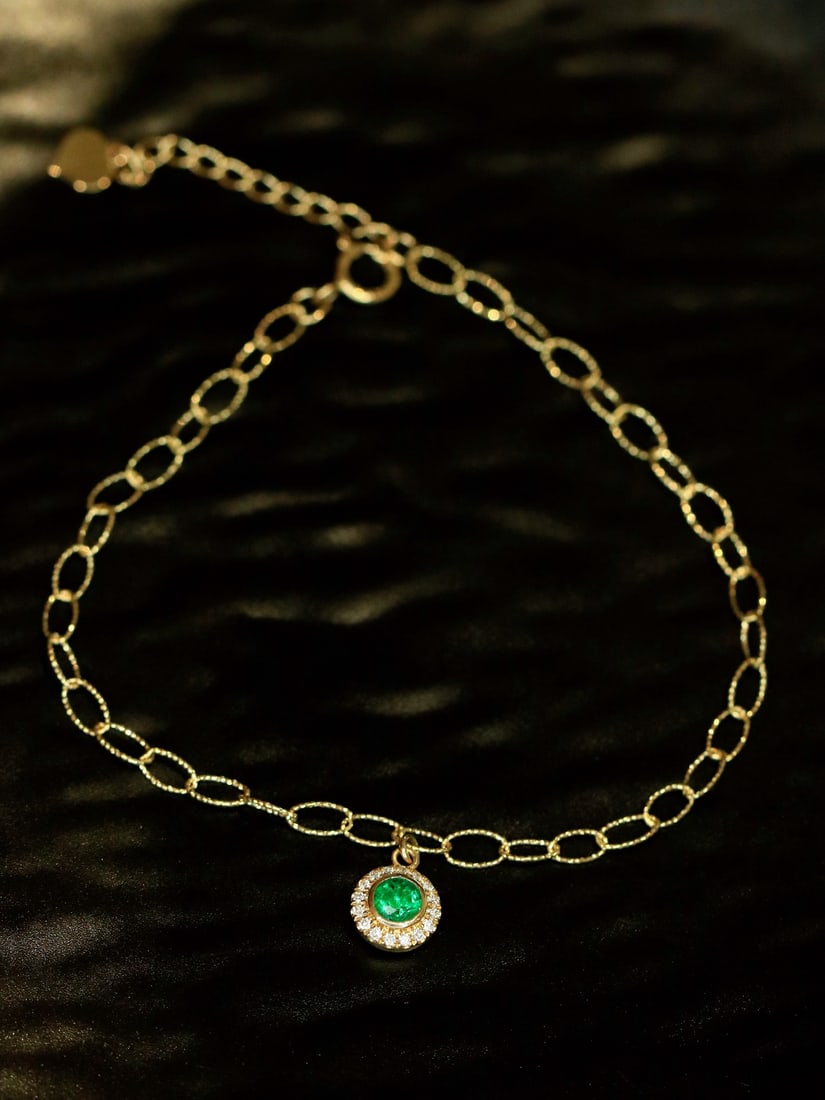 18K Gold Emerald Chain Bracelet: Title: 18K Gold Emerald Chain Bracelet Description: This 18K gold chain bracelet features a captivating emerald, exuding a refreshing green glow. Its exquisite design makes it the perfect accessory