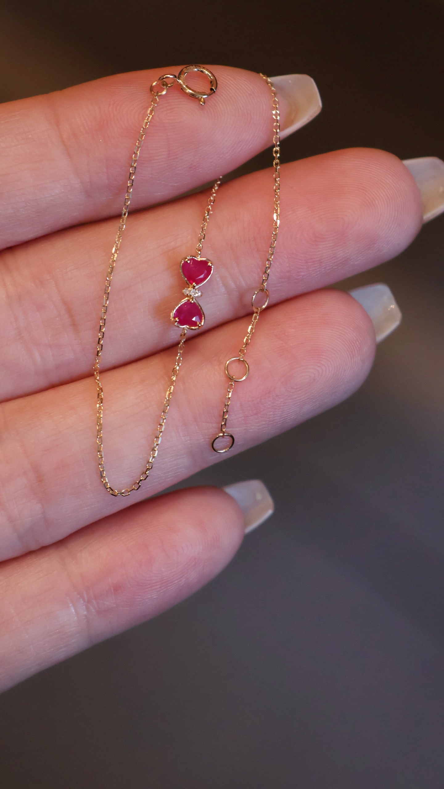 18K Gold Ruby Diamond Bracelet: Title: 18K Gold Ruby Diamond Bracelet Description: This bracelet perfectly combines the elegance of a bow with the fiery passion of two heart-shaped rubies, showcasing a subtle yet exquisite beauty. I