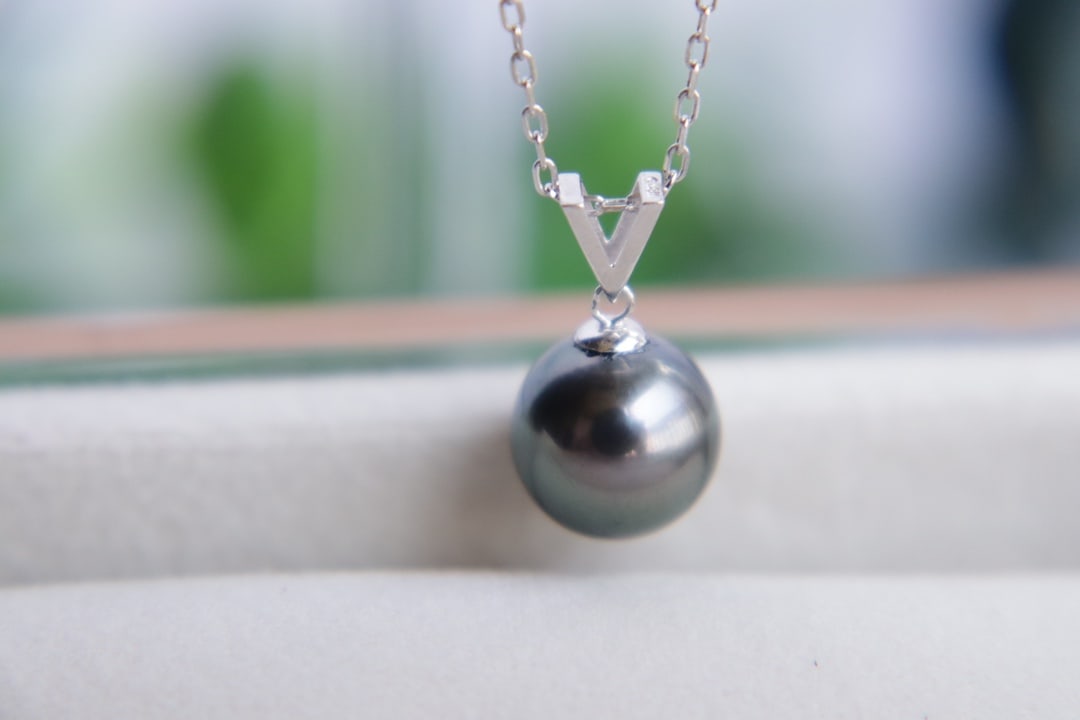 18K Gold Tahitian Pearl Pendant: Title: 18K Gold Tahitian Pearl Pendant Description: This pendant is crafted from 18K gold, featuring a Tahitian pearl that showcases peacock green overtones and a strong luster. The pearl measures
