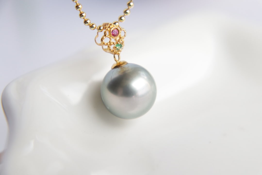 18K Gold Tahitian Saltwater Pearl Pendant: Title: 18K Gold Tahitian Saltwater Pearl Pendant Description: This pendant is meticulously crafted in 18K gold, featuring a Tahitian saltwater pearl that showcases a platinum gray hue and strong luste