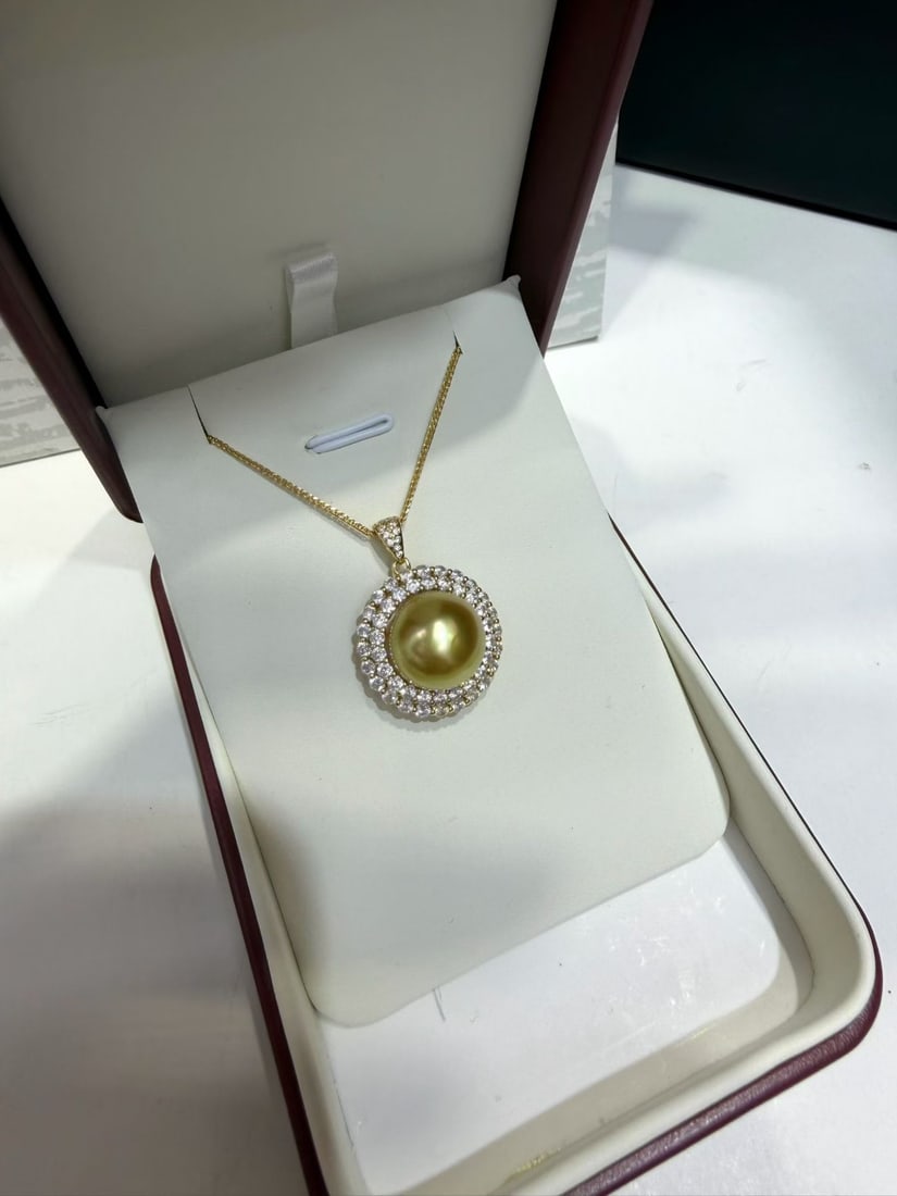 Silver South Sea Golden Pearl Pendant: Title: Silver South Sea Golden Pearl Pendant Description: This pendant features a South Sea golden pearl, showcasing a rich golden luster. The pearl is nearly round with minor blemishes that do not