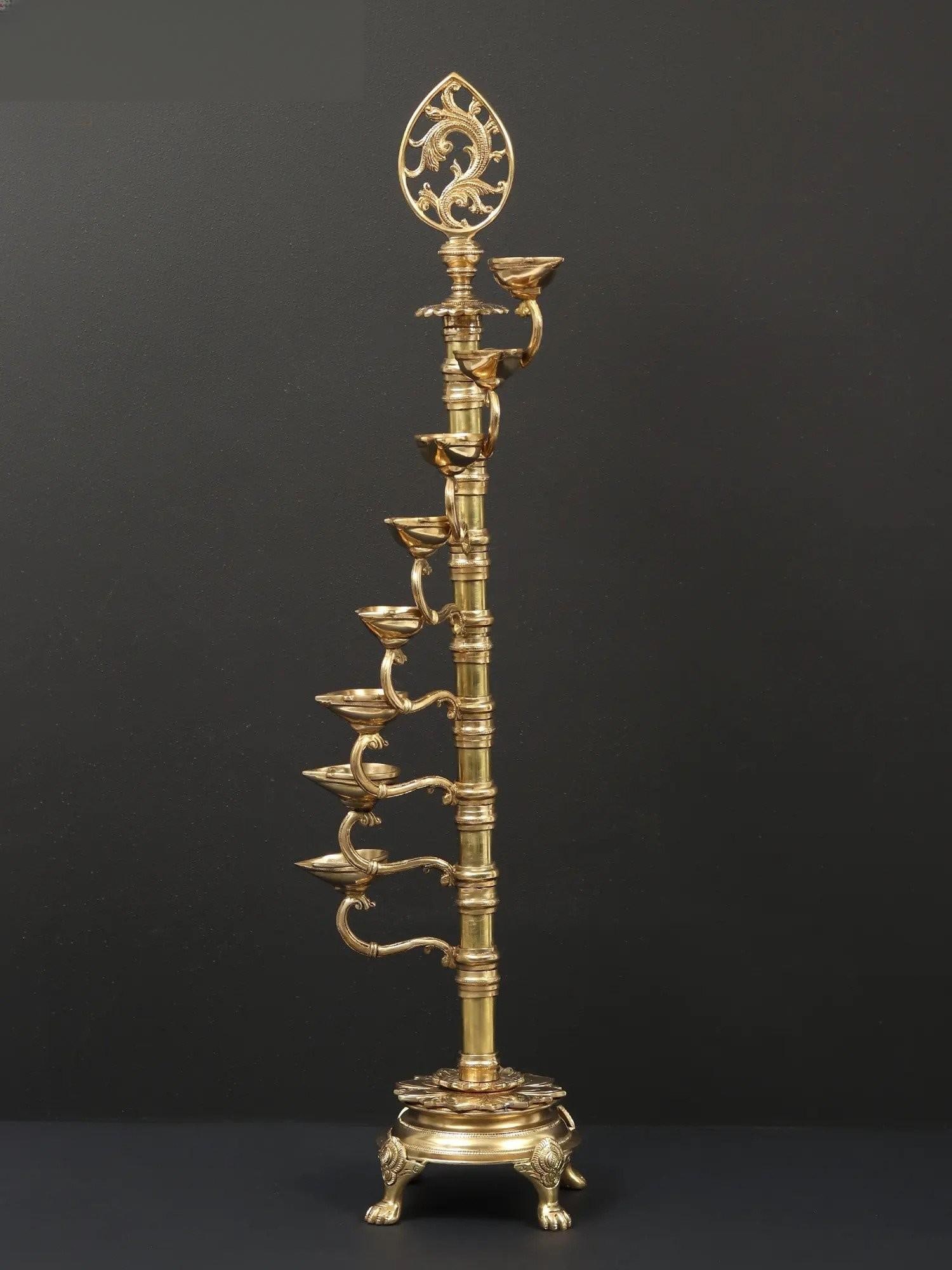 32" Large Eight Wicks Designer Lamp in Brass: Description: This eight-wick standing lamp known as a Nila Vilakku has the auspiciousness of eight lights and a focal picture of a spear. An ornate stand holds the lamp. The lighting is set in the