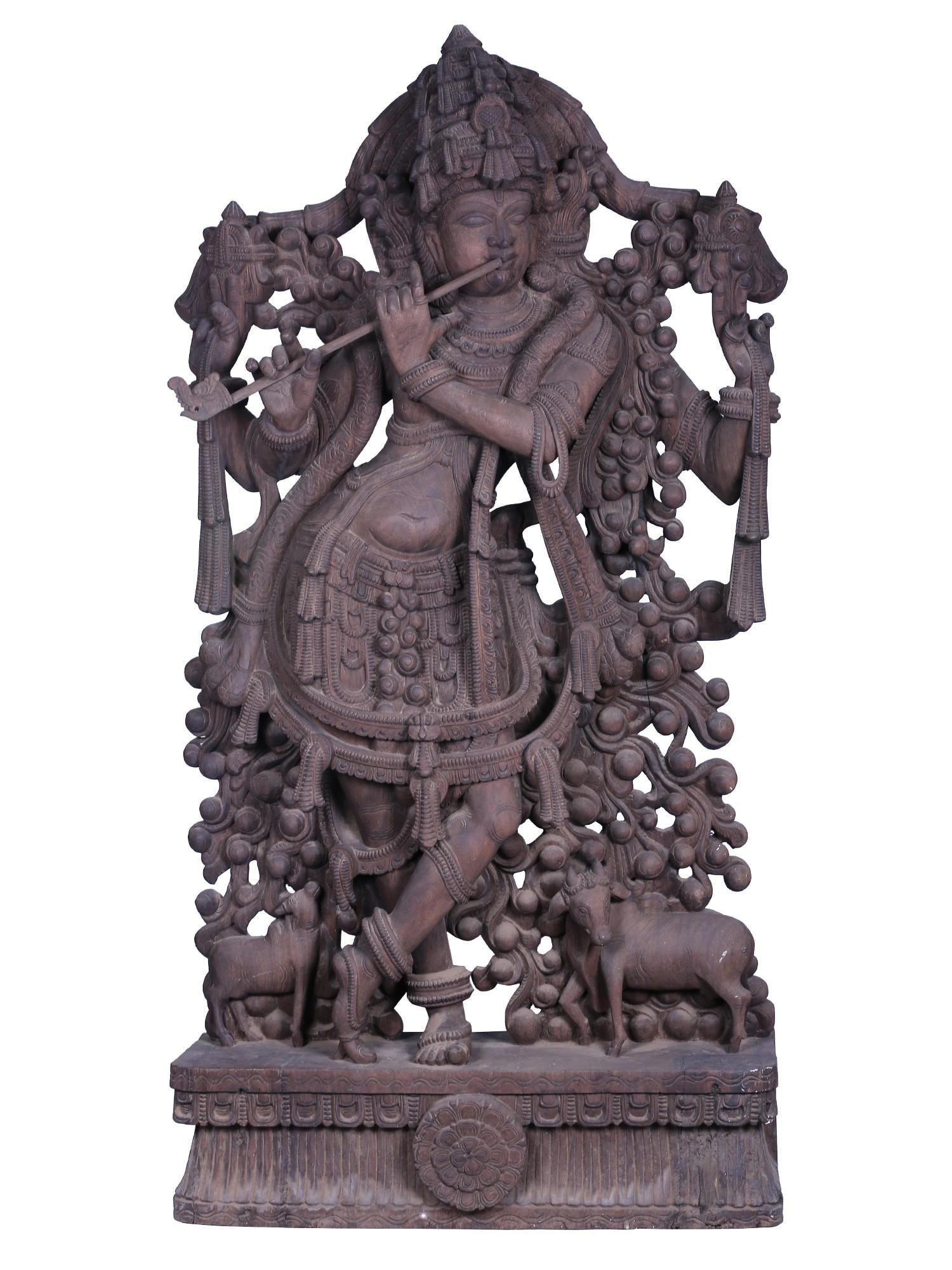 Venugopala Large Wooden Fluting Krishna Idol: Description: Two cows flank the large fluting Krishna statue, one of them lovingly gazing up to catch a glance of their guardian as the other one has its head turned animatedly. The unique purplish