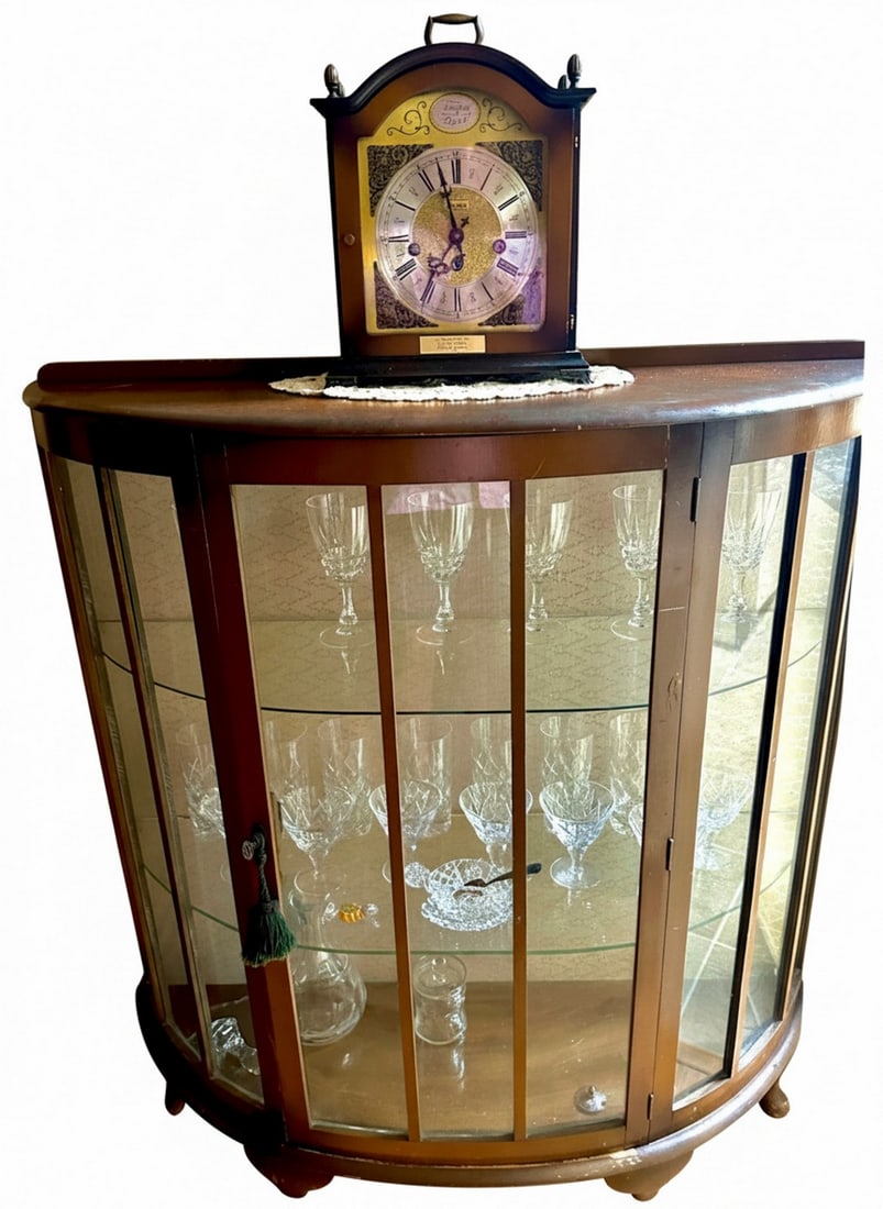 Vintage Curved Front Display Cabinet with Glass Shelves: A vintage wooden display cabinet with a curved glass front and two interior glass shelves, ideal for showcasing collectibles or dinnerware. The cabinet features a warm wood finish and a single door