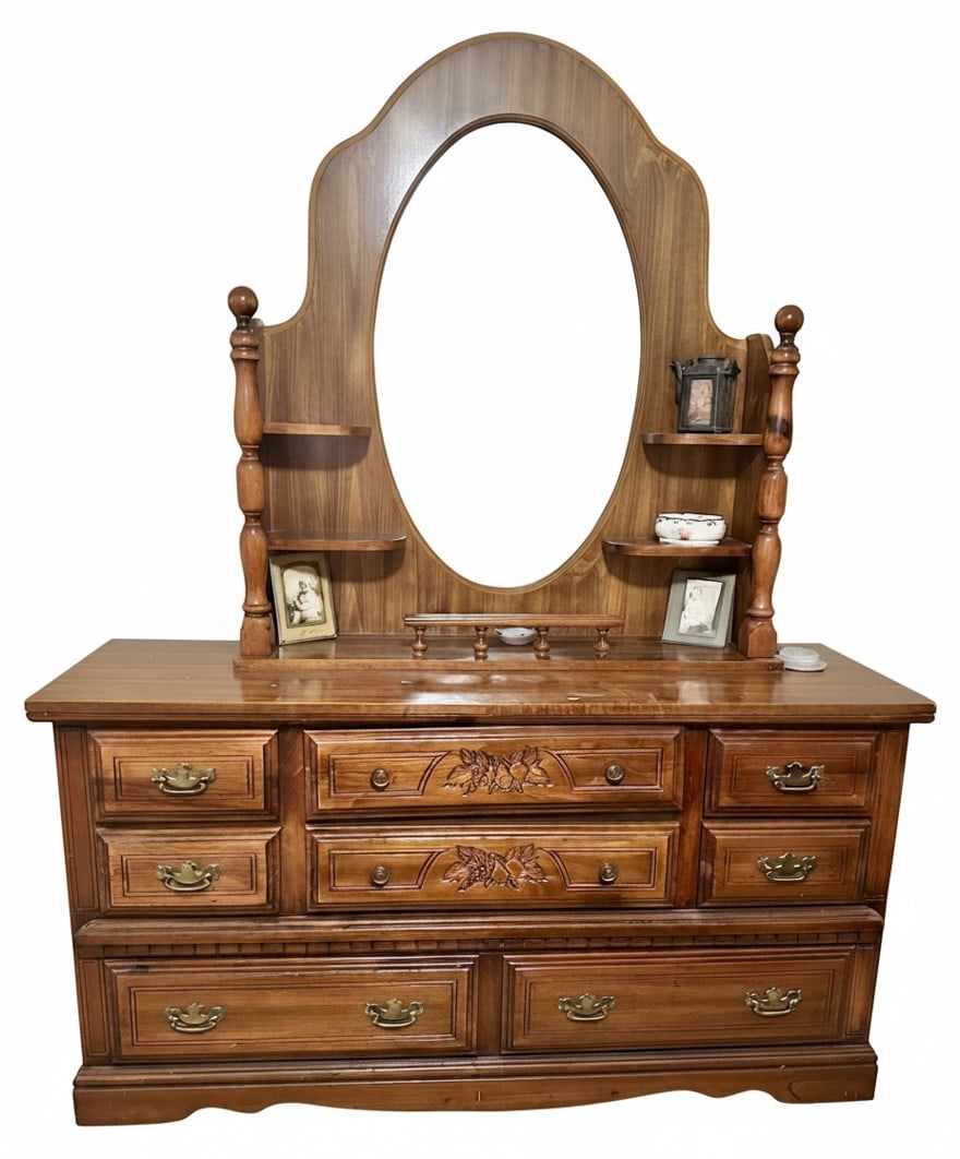 Vintage Wooden Dresser with Mirror: A vintage wooden dresser with an attached mirror, believed to be from the mid-20th century. The dresser features multiple drawers with carved floral accents on the central drawers and brass-toned