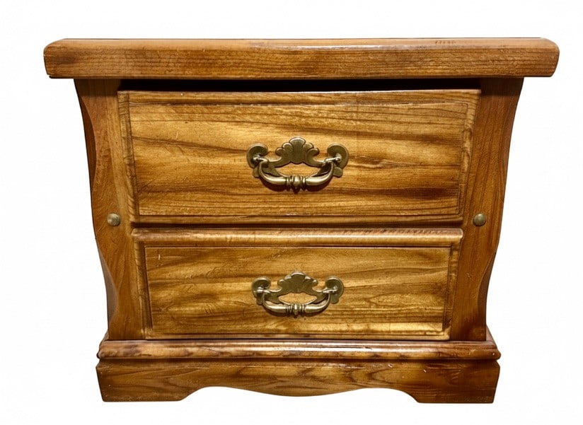 Vintage Style Two-Drawer Nightstand: A vintage style nightstand featuring two drawers with ornate brass-toned pulls and a warm wood finish. The piece has curved side supports and a slightly distressed appearance, reminiscent of French