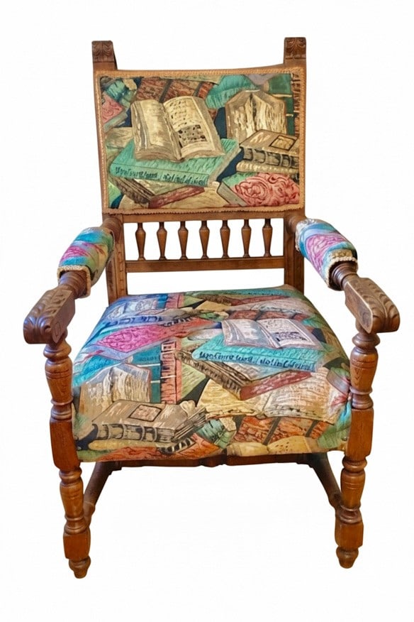 Vintage Carved Oak Armchair with Book-Pattern Upholstery: A vintage carved oak armchair featuring a distinctive book-patterned upholstery on the seat and backrest. The armchair has turned legs, carved armrests, and a spindled back. The fabric depicts