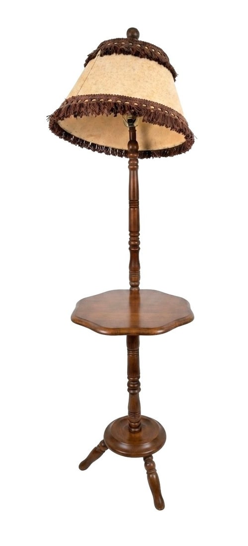 Vintage Wooden Floor Lamp with Integrated Table and Fringed Shade: This vintage wooden floor lamp features a turned wood standard with an integrated octagonal side table, resting on a tripod base. The lamp is topped with a cream-colored fabric shade adorned with