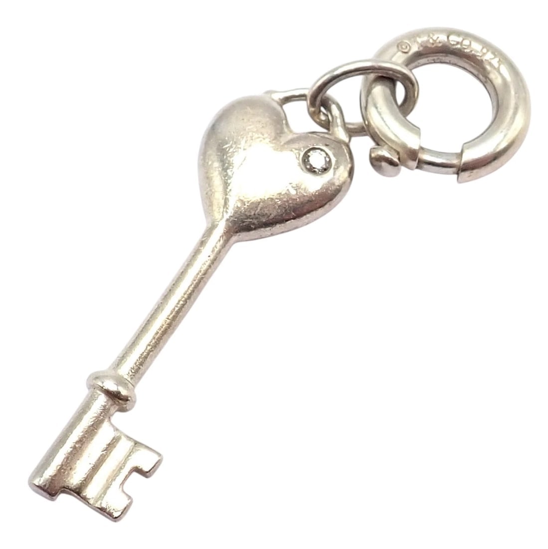 Tiffany & Co. Silver Diamond Key Heart Charm Pendant + Spring Ring Clasp: Tiffany & Co. Silver Diamond Key Heart Charm Pendant with Spring Ring Clasp — Crafted from sterling silver, this elegant charm features a heart-shaped top adorned with a sparkling diamond accent