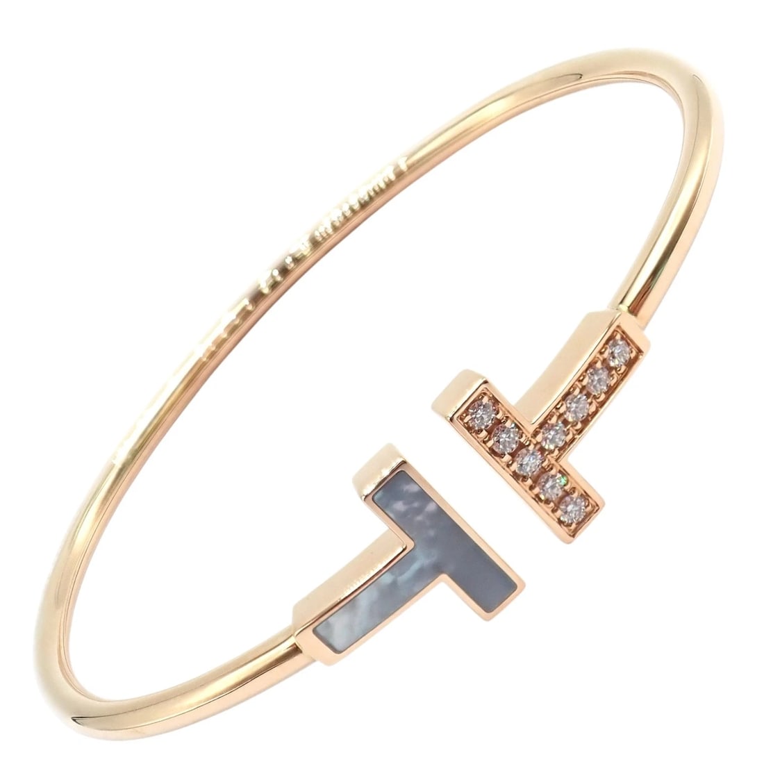 Authentic! Tiffany & Co 18k Yellow Gold Diamond T Wire Mother of Pearl Bracelet: The Tiffany & Co. 18k yellow gold T Wire bracelet featuring the iconic open T motif with luminous mother-of-pearl and sparkling diamond accents. Sleek, modern, and instantly recognizable, this elegant