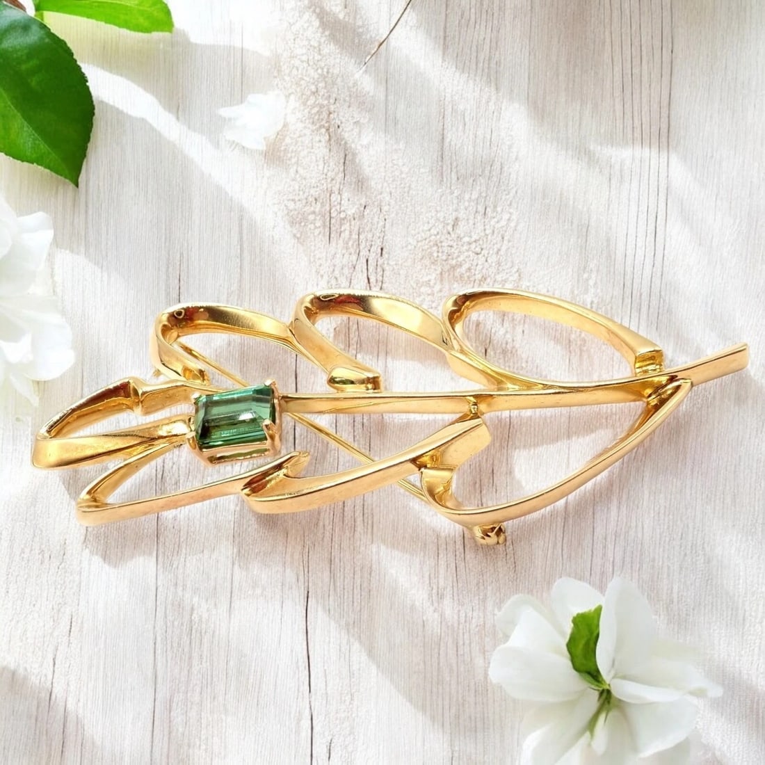 Vintage Tiffany & Co Paloma Picasso 18k Yellow Gold Green Tourmaline Leaf Brooch: Designed by Paloma Picasso for Tiffany & Co. in 1986, this exquisite leaf brooch shimmers in 18k yellow gold. Showcasing a vibrant 1.85ct green tourmaline, it exemplifies timeless elegance, fine craft