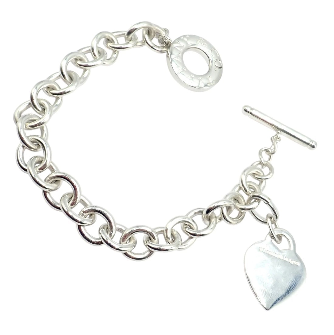 Tiffany & Co Silver Heart Tag Charm + Toggle Bracelet + Oval Jump Ring Clasp: This elegant Tiffany & Co. bracelet is crafted from sterling silver, featuring a classic Tiffany & Co. heart tag charm and a bold oval link design. The bracelet secures with a signature toggle clasp.,