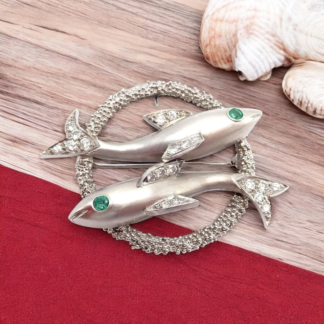 Cartier 18k White Gold Platinum Diamond Emerald Zodiac Pisces Fish Brooch Pin: A mesmerizing testament to Cartier’s iconic luxury, this Rare Vintage Pisces Two Fish Brooch showcases an exquisite zodiac motif in 18k white gold and platinum. Brilliant diamonds adorn the capt