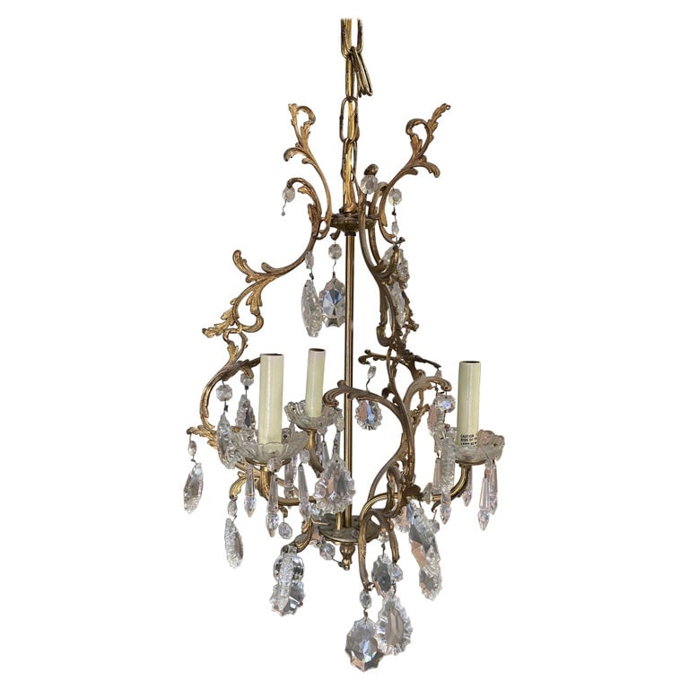 Tall Hollywood Regency Crystal and Brass Chandelier w/ Three Lights: An elegant 20th century Hollywood Regency crystal and brass chandelier. This chandelier has three light that have been electrified and surrounded with sparkling crystals Measurement: width 24",