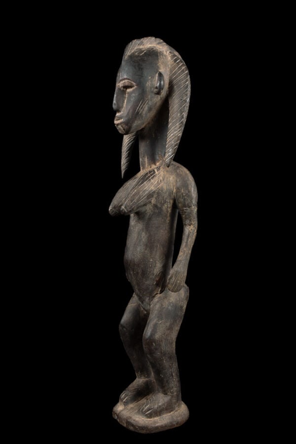 Ancestor Figure - Wood - Bambara - Mali: Stylistic wooden ancestor statue of the Bambara tribe from Mali. The Dyonyeni are associated with the southern Dyo and Kwore society. These female statues usually appear with large conical breasts