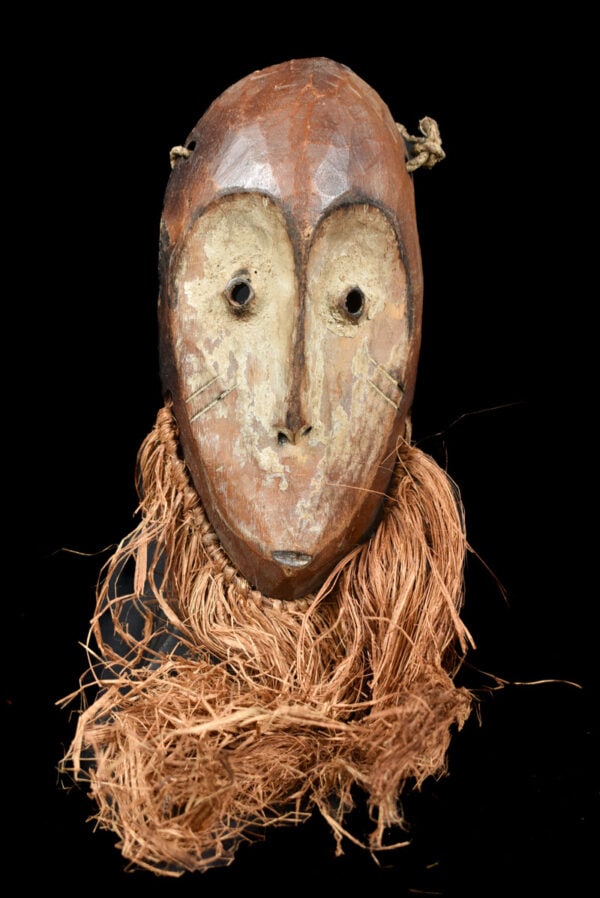 Mask - Wood, Raphia - Lega - Congo: Lovely Lega Mask from Zaire or Congo. Wood with multi-layered patina. Remains of offerings, mica powder, kaolin. Condition: good with a beautiful aged patina due to tribal use. Covered in Pembe,