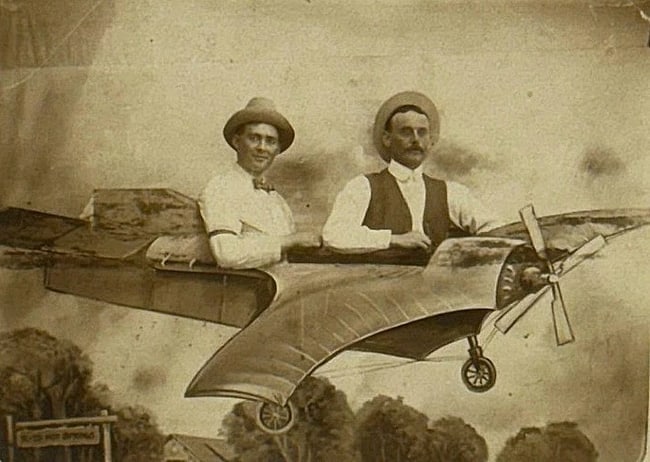 Real Photo PC Men in Fantasy Plane 1900: Real photo postcard of 2 men in a studio fantasy plane. Sign says '...Hot Springs'. Card is in good condition with a corner crease and is postally unused. Image is sharp. Please see images. Early
