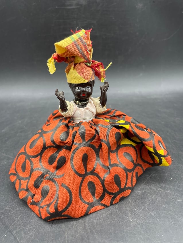 Vintage Black Americana Cloth Skirt Doll Figurine Pin Cushion Style Folk Art Figure: Date/Period: Circa 1940s-1960s Dimension: Approx 5 x 5 Material: The figure appears to be constructed of molded plastic or a comparable composition material, with textile clothing and headwrap