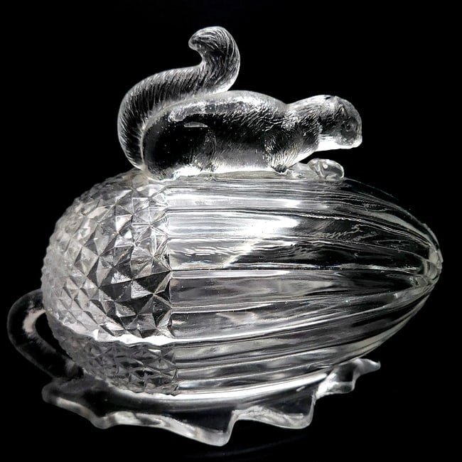 LE Smith Clear Cut Glass Squirrel Topped Acorn Dish: LE Smith Clear Cut Glass Squirrel Topped Acorn Dish Measures approx 6"H x 8L clear glass Covered dish is in the design of a squirrel sitting on an acorn. No chips or cracks Shipping: Domestic: