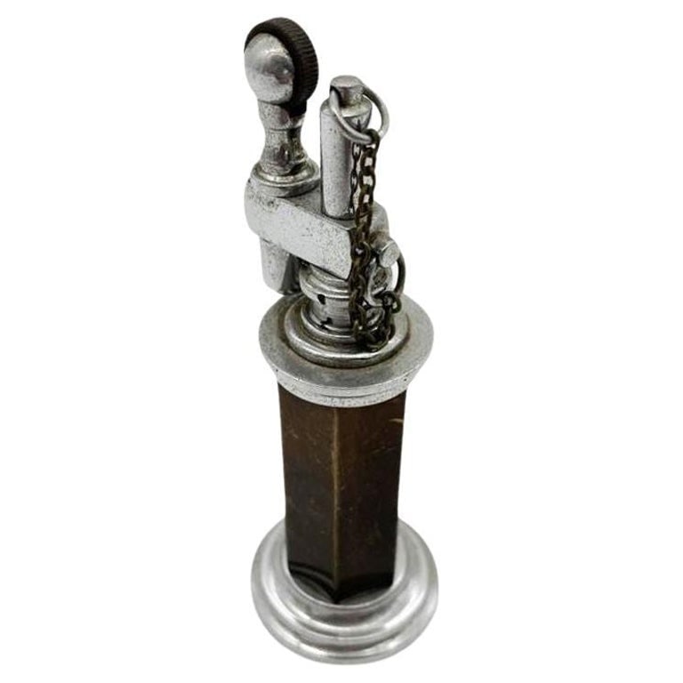Green and Silver "Column" Petrol Table Chain Lighter by Daltis: Green and silver column table petrol lighter with chain cap by Daltis New York City. Measures: 5.5" tall x 2.5" base diameter. Reserve: $225.00 Shipping: Domestic: Shipping rates are determined by