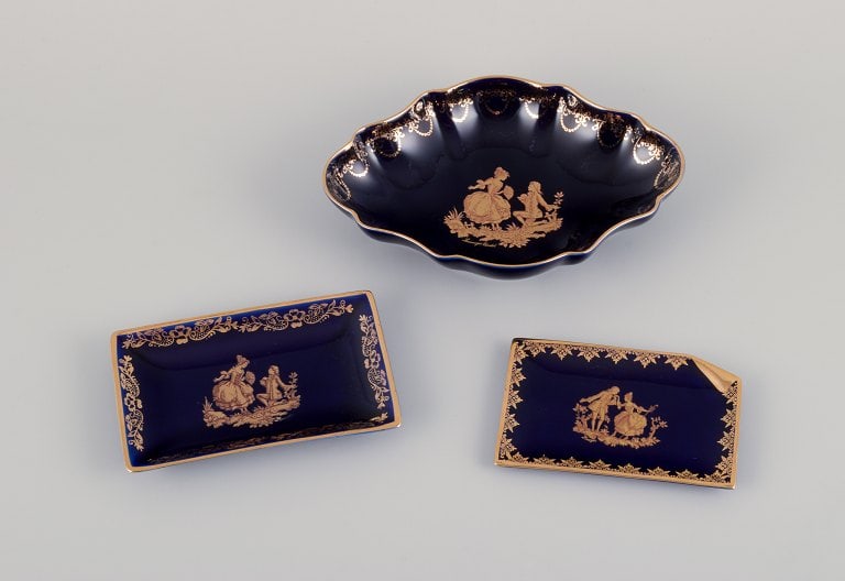 Limoges, France. Bowl and two small trays in porcelain. Decorated with 22-karat gold leaf and: Limoges, France. Bowl and two small trays in porcelain. Decorated with 22-karat gold leaf and beautiful royal blue glaze. Sceƒe¨ne galante. Approximately from 1970. Provenance: From a large French