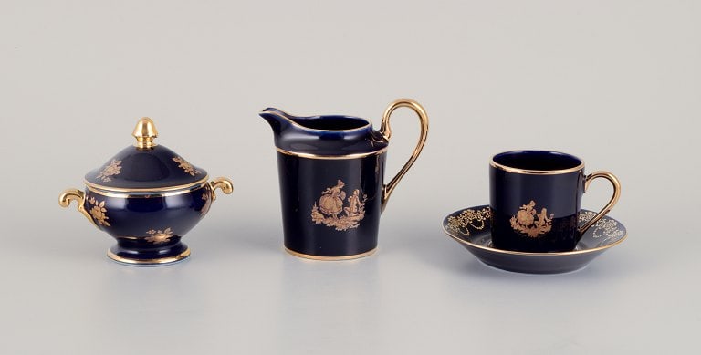 Limoges, France. Coffee cup, sugar bowl, and creamer in porcelain decorated with 22-karat gold leaf: Limoges, France. Coffee cup, sugar bowl, and creamer in porcelain decorated with 22-karat gold leaf and beautiful royal blue glaze. Sceƒe¨ne galante. Approximately 1970. Provenance: From a large