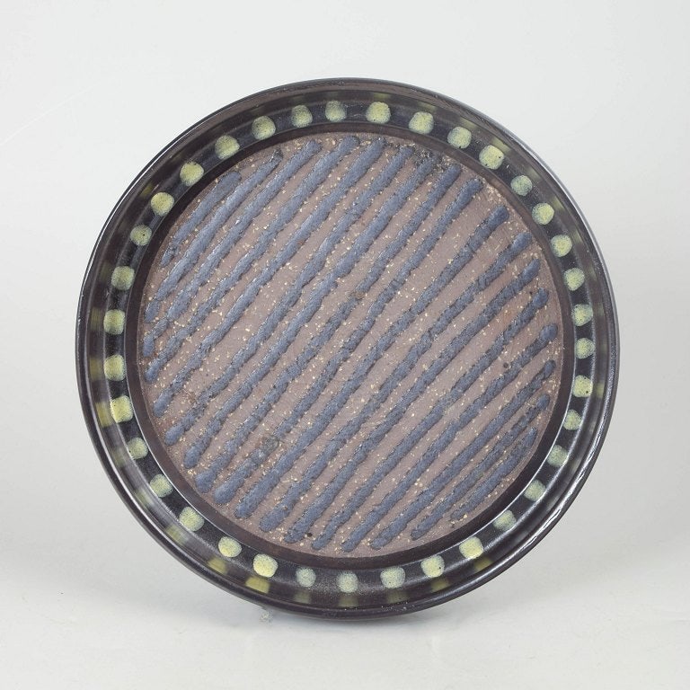 Mari Simmulson for Upsala Ekeby, Sweden. Round ceramic dish with diagonal relief pattern. Approx.: Mari Simmulson for Upsala Ekeby dish model 5056. Decorative Swedish ceramic dish in round form with hand-decorated diagonal relief pattern and dotted border decoration, executed in dark glaze with sub