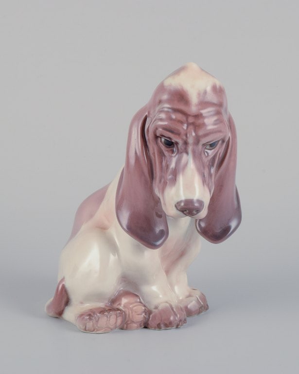 Dahl Jensen porcelain figurine of a sitting Basset Hound.: Dahl Jensen porcelain figurine of a sitting Basset Hound. Model: 1065. From the 1930s. in perfect condition. First factory quality. Dimensions: H 14.0 cm x W 10.0 cm. Reserve: $266.00 Shipping:
