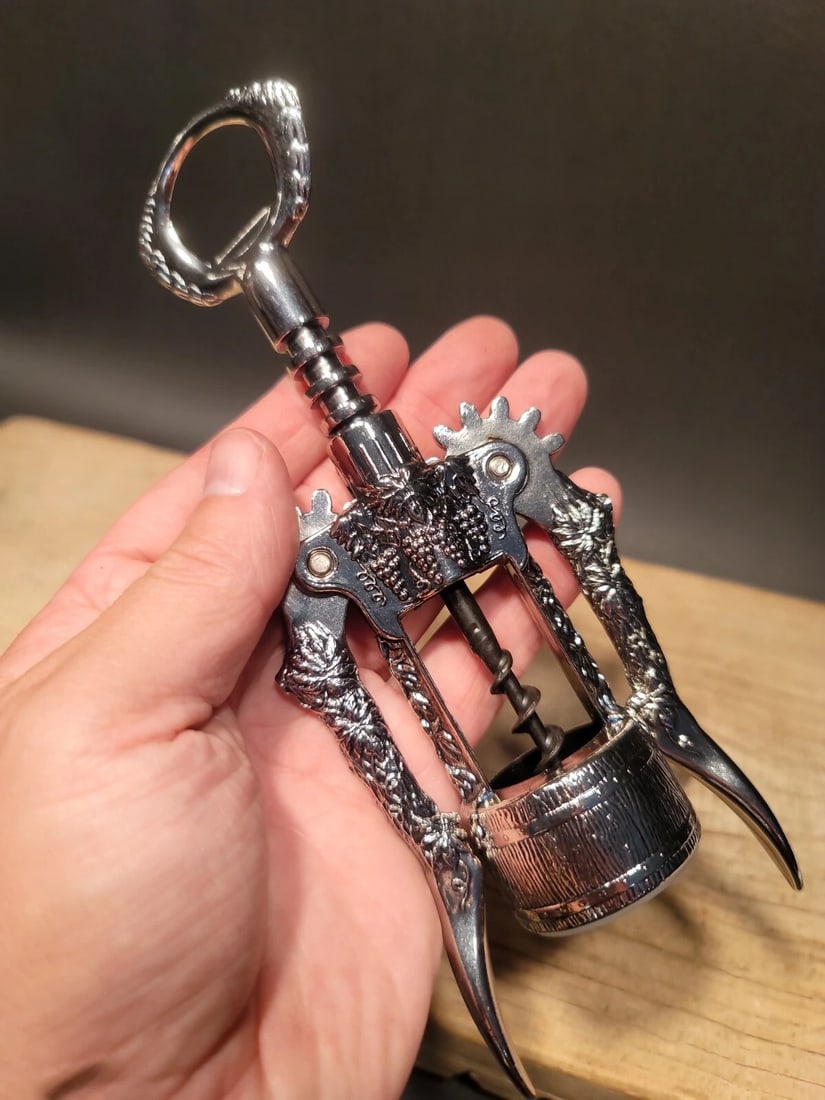 Ghidini Italy Wine Bottle Corkscrew Opener: 8" Tall x 3" Wide Such a neat vintage style Ghidini corkscrew made in Italy. As you can see the corkscrew is covered in grape and wine barrel designs. Nice heavy metal design. New in the box never