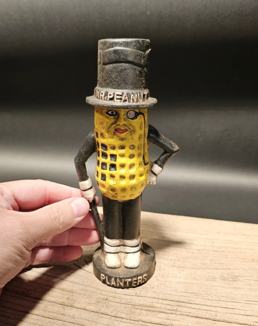 Cast Iron Peanut Coin Bank: 7 1/2" Tall x 3 1/2" wide Wonderful cast iron reproduction antique coin bank. As you can see this coin bank looks like an original! See the images for the best details. Such a neat collectible!