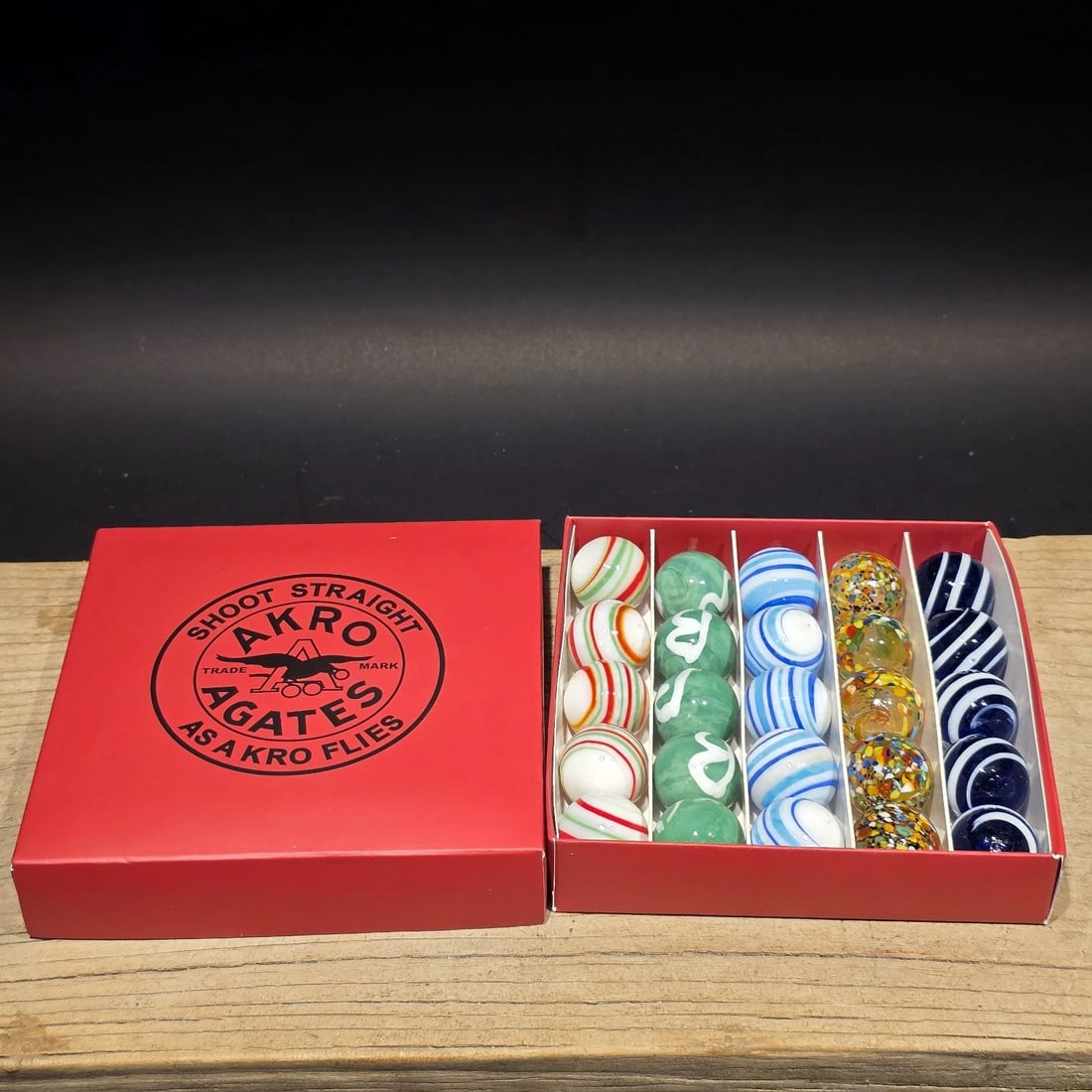 Akro Agates Box Set of Marbles: Akro Agate-Style "Straight Shooters" Marble Set (Reproduction) This boxed marble set is a modern reproduction inspired by classic Akro Agate designs, featuring familiar swirl and corkscrew patterns