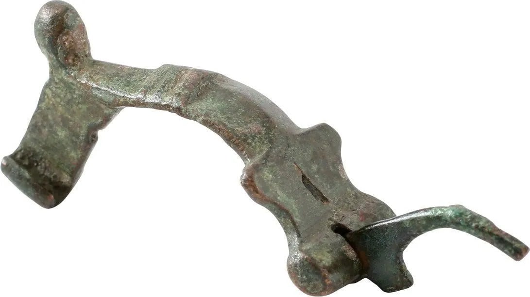 ROMAN FIBULA (BROOCH), LATE 2ND-5TH CENTURY AD: Bronze, 1 3/8" length. Elegant tapered bow with a flared base and transverse medial. Knob terminal. Riha (Die romischen Fibeln aus Augst und Kaiseraugst) type B3 with independent spring on an axel