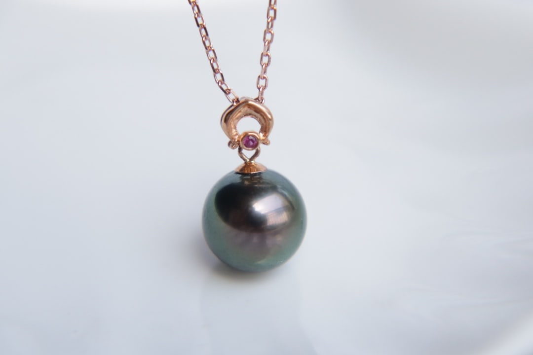 18K Gold Natural Tahitian Sea Pearl Pendant: Title: 18K Gold Natural Tahitian Sea Pearl Pendant Description: This 18K gold pendant features a round Tahitian sea pearl with a diameter of 9.8mm, showcasing a peacock green base color. The slight im