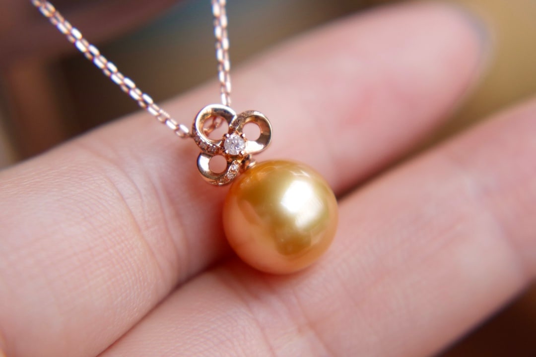 18K Gold Flawless Sea Pearl Pendant: Title: 18K Gold Flawless Sea Pearl Pendant Description: This pendant is meticulously set in 18K gold, featuring a round sea pearl that showcases a rich golden luster, flawless and captivating. Its bea