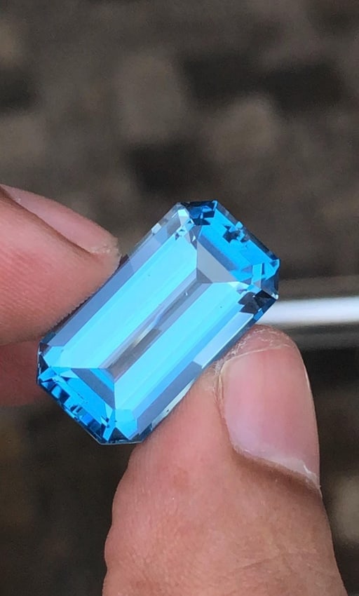 20.825 Carat Emerald Cut Swiss Blue Topaz Gemstone For Jewellery: Introducing a magnificent Swiss Blue Topaz gemstone. Its Classy Emerald Cut, which sparkles wonderfully, stands for prosperity and love. This jewel is exquisitely carved and emanates grace and charm. 