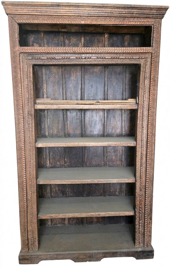 Carved Wooden Bookcase or Display Cabinet: A heavily carved wooden bookcase or display cabinet, likely of Indian or Southeast Asian origin. The piece features intricate, repeating geometric and floral motifs carved into the frame and shelving