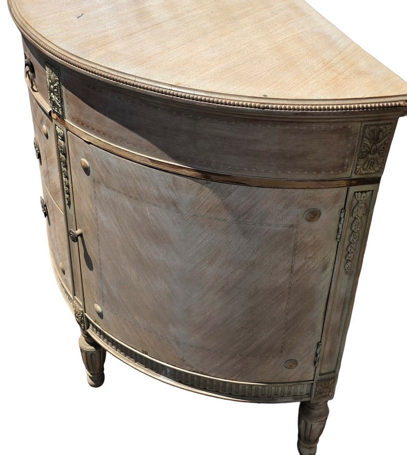 Continental Neoclassical Style Demilune Console Table: A demilune console table in the Continental Neoclassical style. The table features a semicircular top, carved floral and foliate motifs, and fluted tapered legs. The finish appears to be a distressed