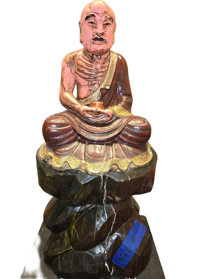 Polychrome Carved Wood Luohan Figure: A polychrome carved wood figure depicting a seated arhat or Luohan, likely from the late 19th or early 20th century. The figure is shown with exposed ribs and a contemplative expression, holding a