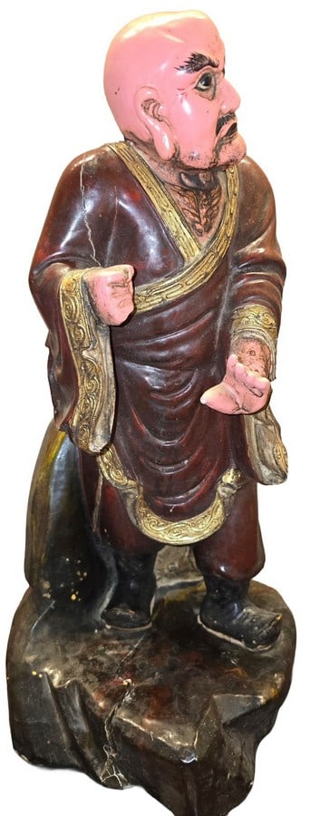 Vintage Polychrome Lacquered Wooden Monk Figure: A vintage polychrome lacquered wooden figure depicting a monk or arhat. The figure features a pink-painted face and hands, black painted hair and beard, and a deep red robe with ornate gold and black