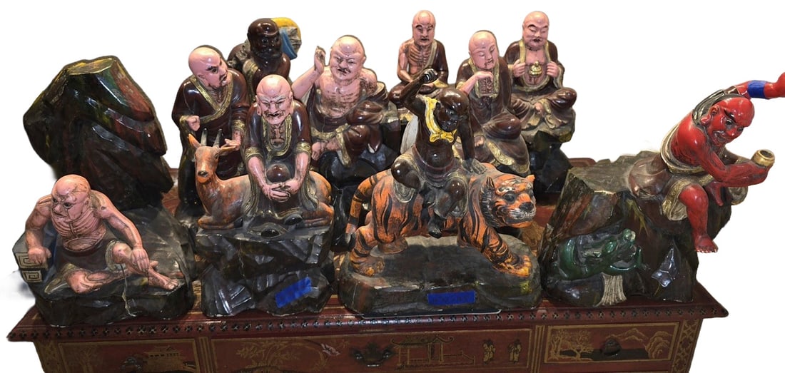 Collection of 12 Chinese Polychrome Painted Clay Luohan Figures: A collection of 12 Chinese polychrome painted clay figures depicting various Luohan (arhats) in different poses, some seated on animals such as tigers and deer, and others engaged in contemplative or