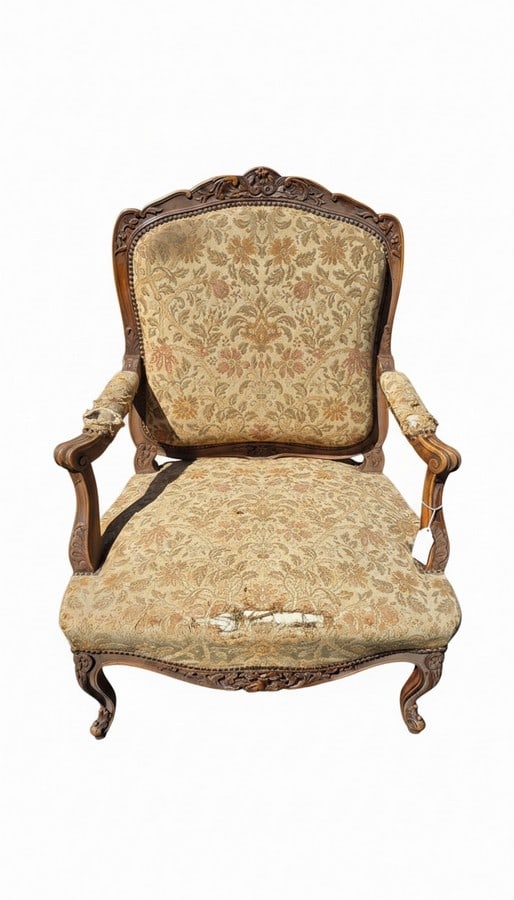 Pair of French Provincial Carved Armchairs: A pair of French Provincial style carved armchairs with ornate floral upholstery. The chairs feature rococo-inspired carvings on the wooden frames, cabriole legs, and a distressed finish. The fabric
