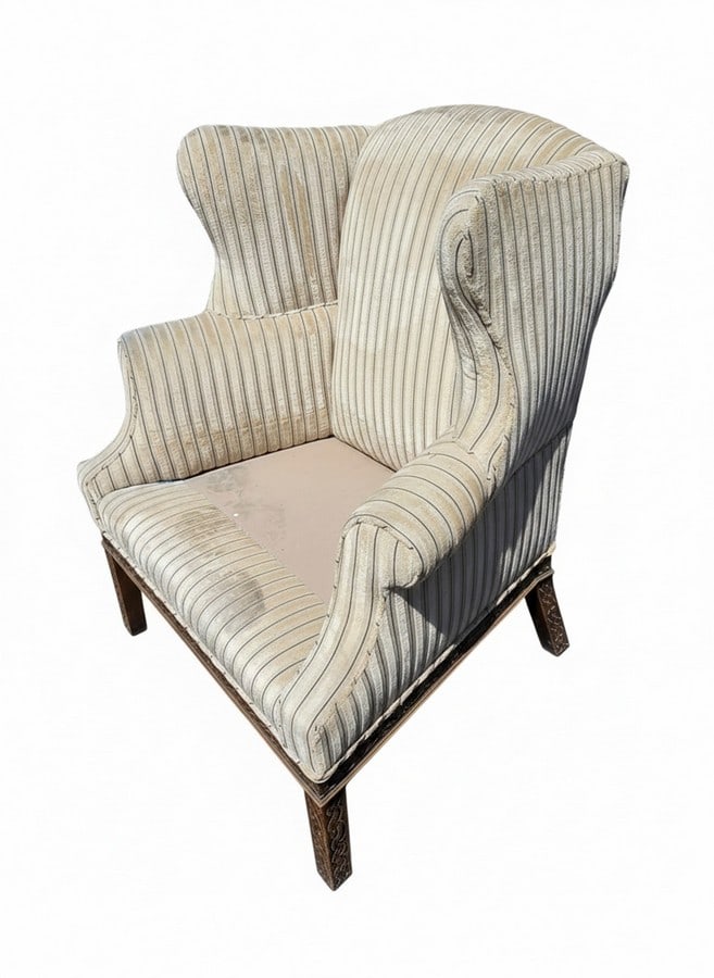 Vintage Striped Upholstered Wingback Armchair: A vintage upholstered wingback armchair featuring a striped pattern in cream and beige tones. The chair has traditional wingback arms and a loose seat cushion. The wooden legs are visible at the base.