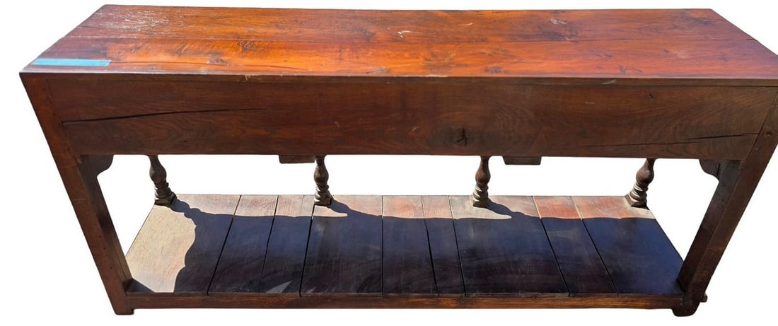 Rustic Console Table with Three Drawers: A rustic console table crafted from dark wood, featuring a rectangular top, three small drawers with ornate brass-toned pulls, and a lower slatted shelf. The front apron of the table has a decorative 