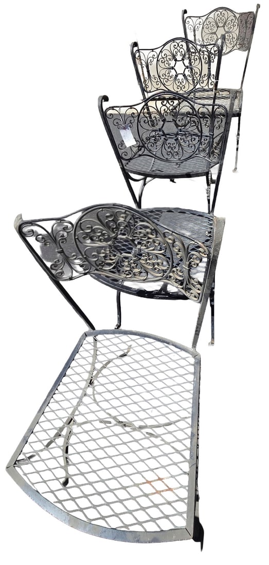 Set of Four Wrought Iron Patio Chairs: A set of four wrought iron patio chairs, likely mid-20th century, featuring scrolled backrests and expanded metal seats. The dark finish suggests they are intended for outdoor use. The intricate