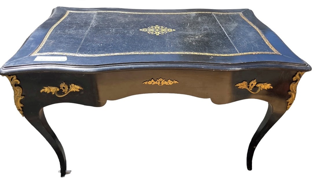 Louis XV Style Black and Gilt Decorated Writing Desk: A sophisticated writing desk in the Louis XV style, featuring a black lacquered finish with ornate gilt decoration. The top surface is adorned with a central gilt motif and a decorative gilt border, s
