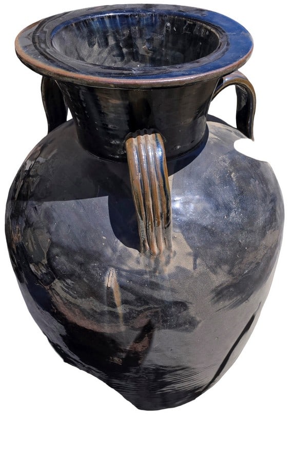 Large Black Glazed Ceramic Handled Pot: A substantial ceramic pot with a glossy black glaze, featuring a wide flared rim and two ribbed handles. The glaze shows some distressing, suggesting age and outdoor use. The interior also appears