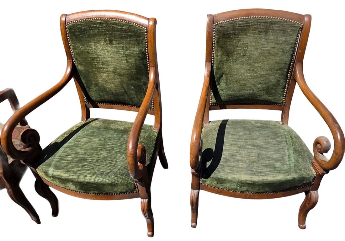 Pair of Antique Green Velvet Armchairs: A matching pair of antique armchairs featuring carved wooden frames, scrolled arms, and green velvet upholstery with brass nailhead trim. The wood appears to be a rich, dark tone, possibly mahogany