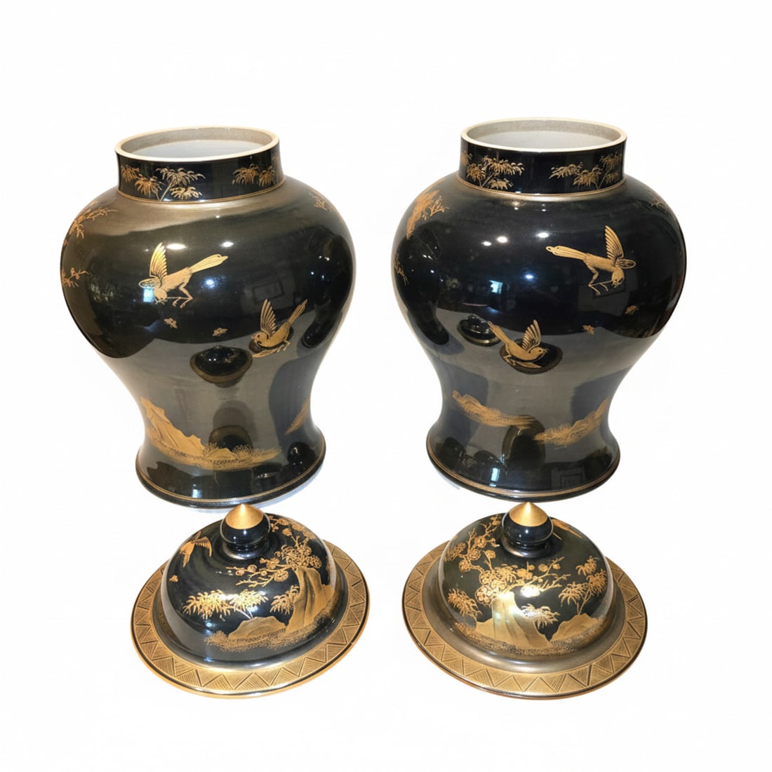 Pair of Black and Gilt Chinoiserie Ginger Jars: A matching pair of ginger jars, featuring a black glazed ground with intricate gilt chinoiserie decoration depicting birds, trees, and landscapes. The jars come with their original domed lids, also