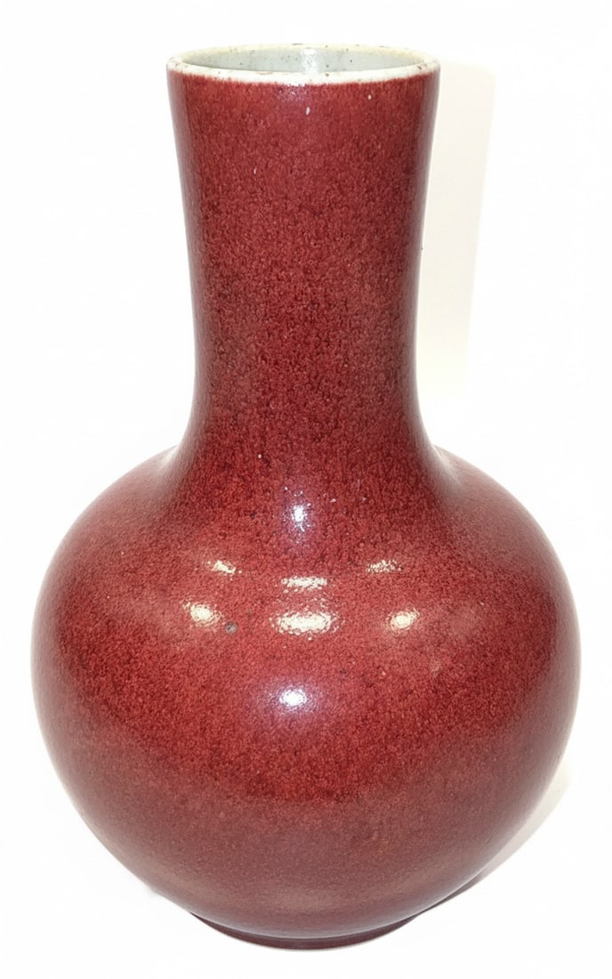 Chinese Sang de Boeuf Glazed Porcelain Vase: This is a Chinese Sang de Boeuf glazed porcelain vase, featuring a classic globular body and a slender neck with an everted rim. The vase is covered in a rich, speckled oxblood red glaze, with a