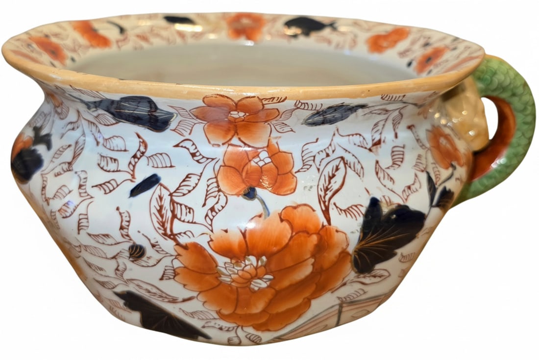 Ironstone China Floral Chamber Pot with Serpent Handle: This antique Ironstone China chamber pot features a vibrant floral pattern in orange, red, and dark blue on a white ground. The design includes large blossoms and delicate foliage. A distinctive serpe
